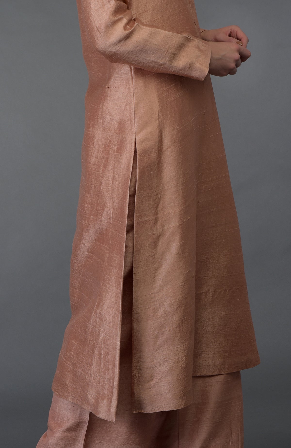 A person models a pressed rose raw silk suit with a long kurta and palazzo pants.