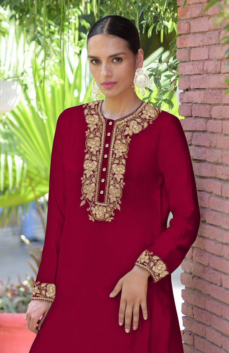 A woman models a blood red Kashmiri Tilla embroidered kurta set with gold embroidery.
