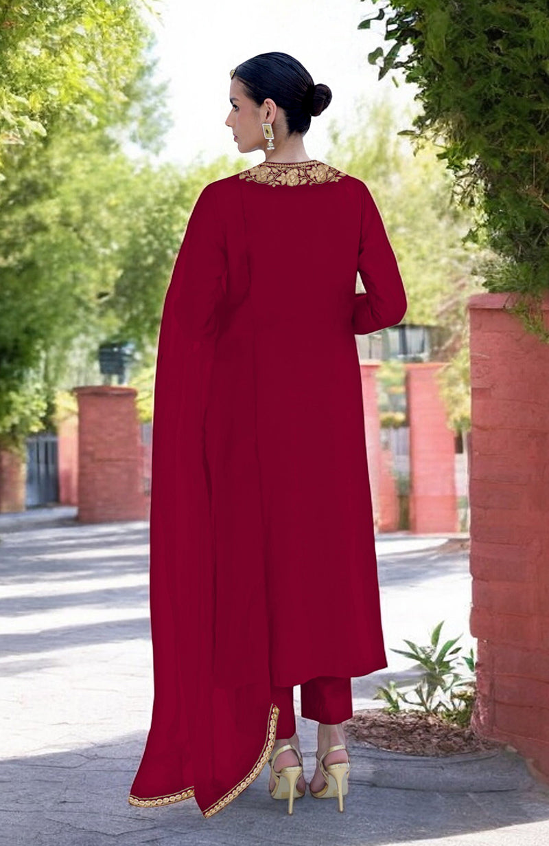 A woman in a blood red Kashmiri Tilla embroidered kurta set stands outdoors.