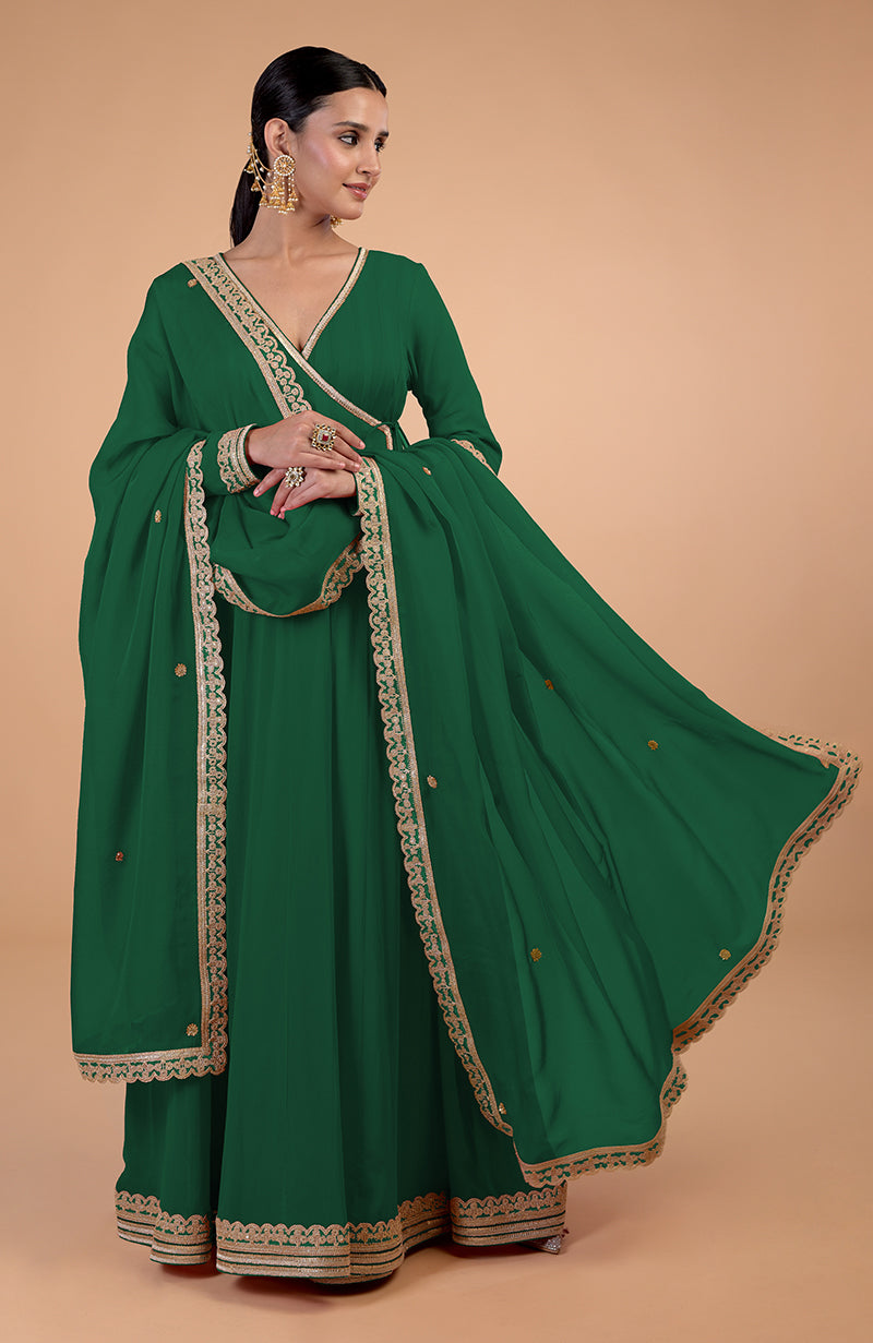 A woman models a green Angrakha Anarkali set with gold Gota Patti embroidery.