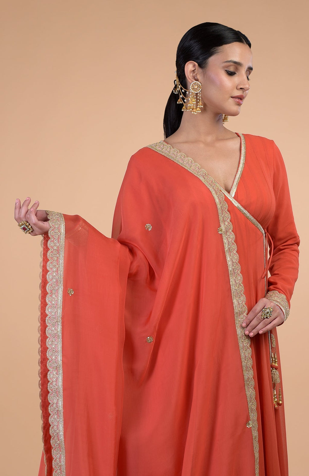 A model wears a burnt orange Angrakha Anarkali set with gold Gota Patti embroidery.