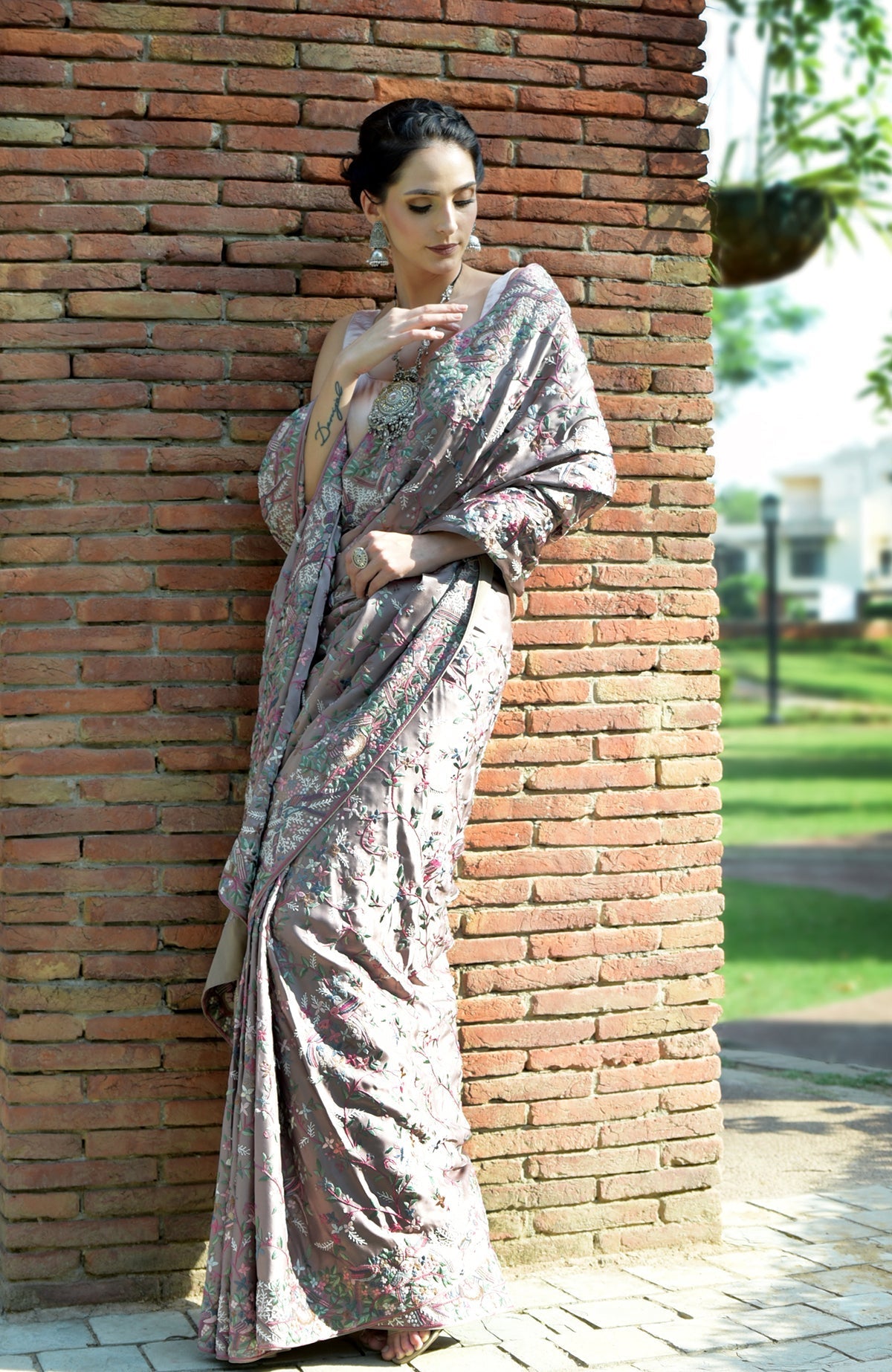 A woman models a tea rose Parsi Gara hand-embroidered saree with floral and bird motifs.