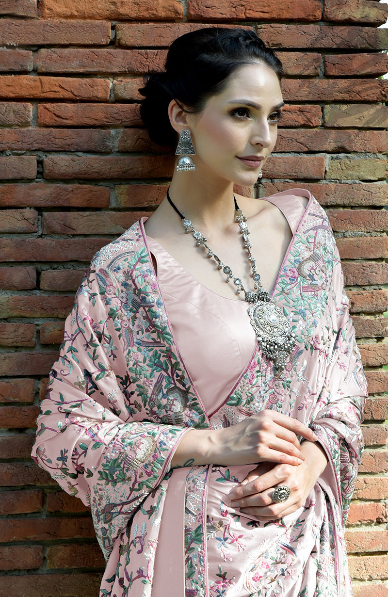 A woman models a pale pink Parsi Gara hand-embroidered saree with a matching blouse.