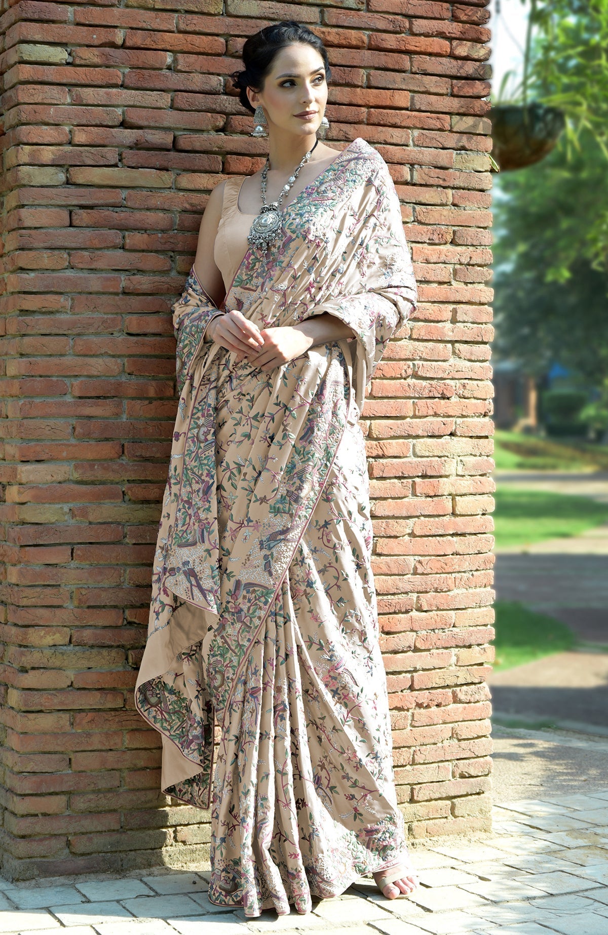 A woman models a tea rose Parsi Gara hand-embroidered pure satin silk saree.