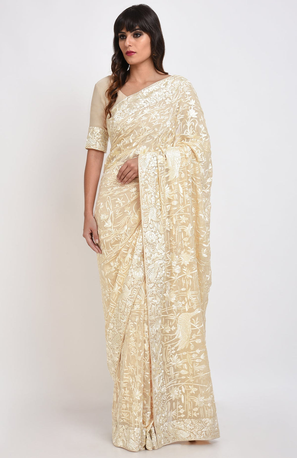 A woman models a fawn Parsi Gara hand-embroidered saree with floral and bird motifs.