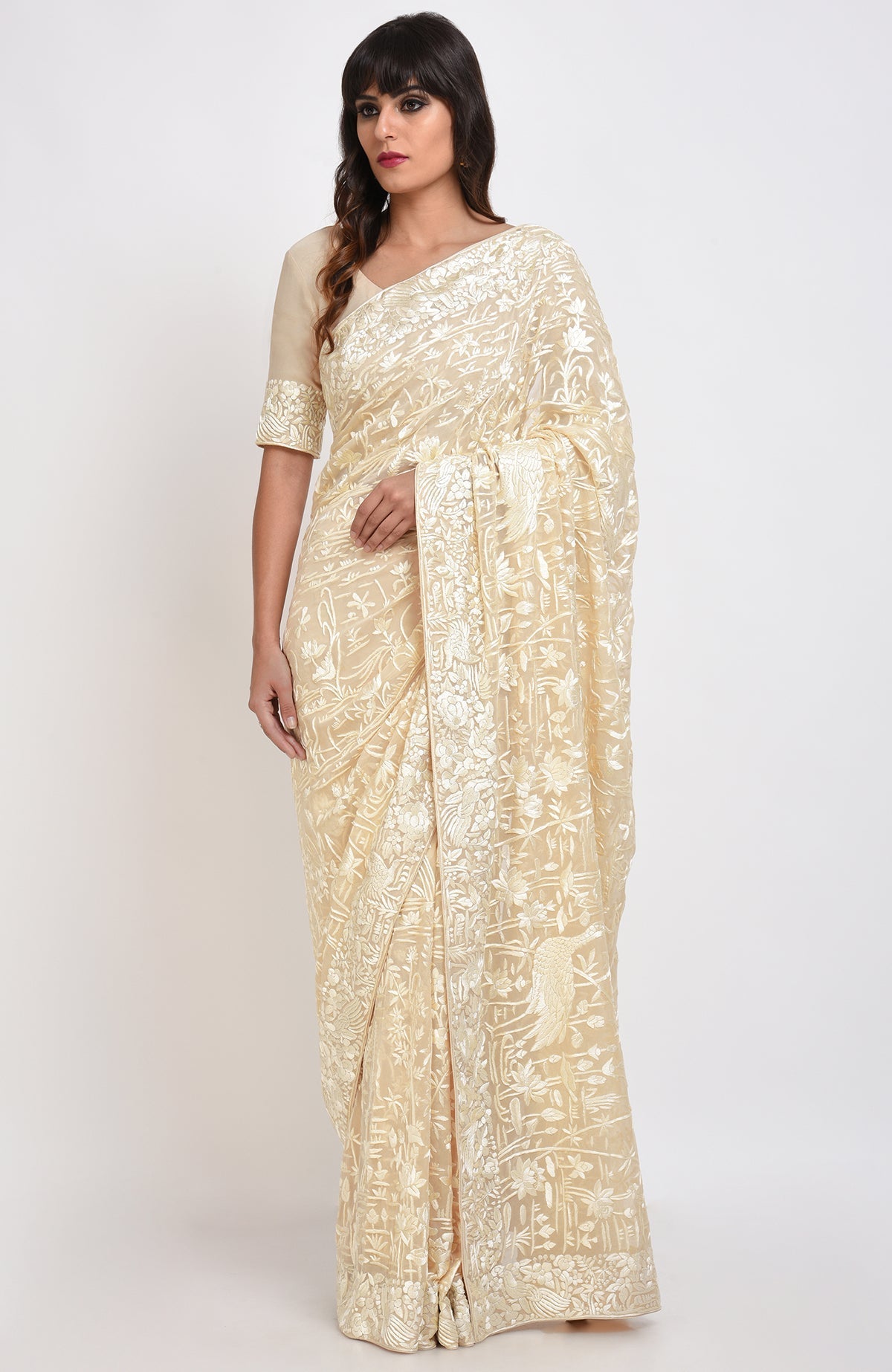 A woman models a fawn Parsi Gara hand-embroidered saree with floral and bird motifs.