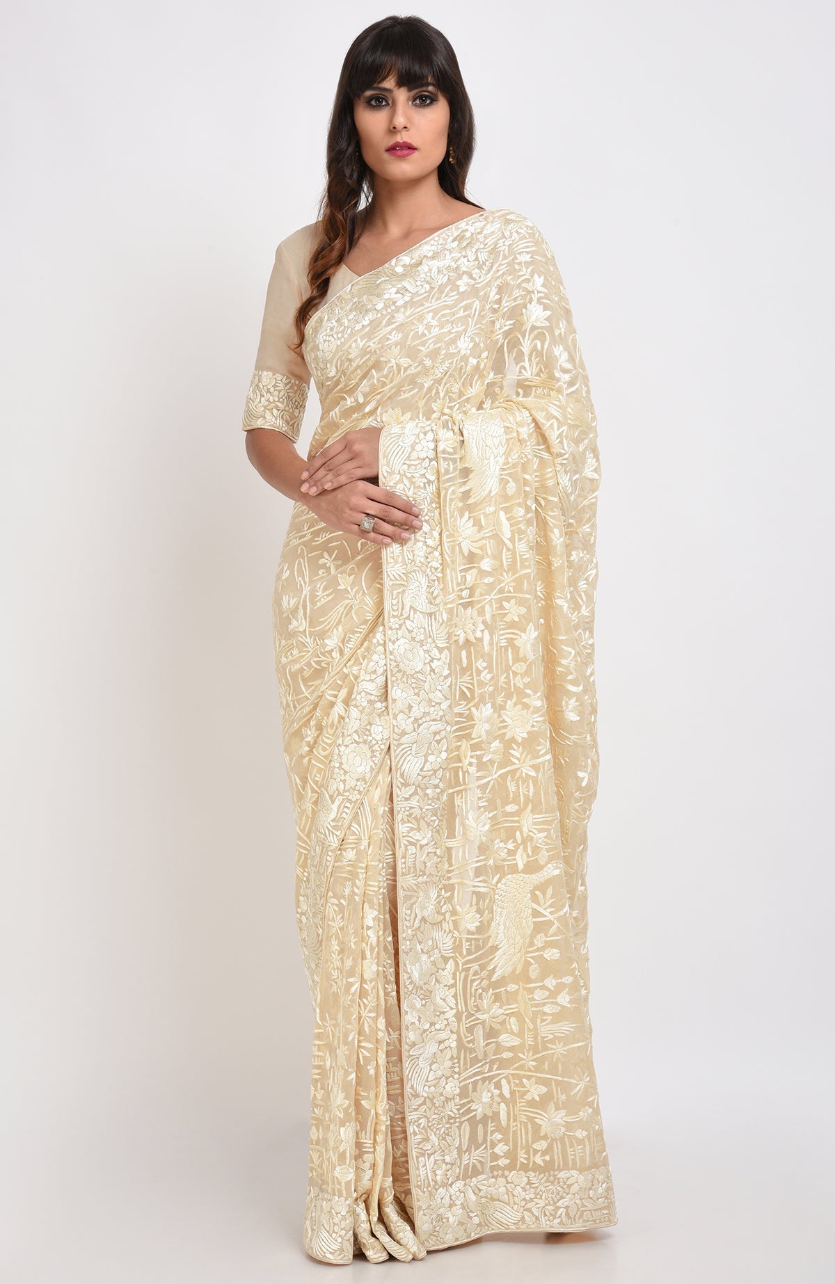 A woman models a fawn Parsi Gara hand-embroidered saree with floral and bird motifs.