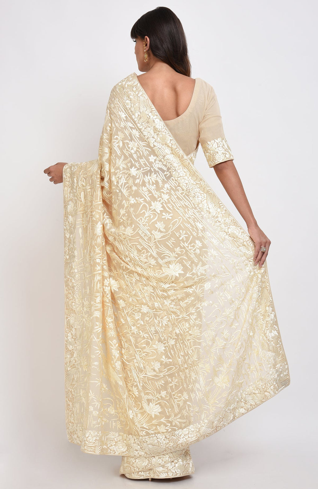 A woman from behind wearing a fawn Parsi Gara hand-embroidered saree with floral patterns.