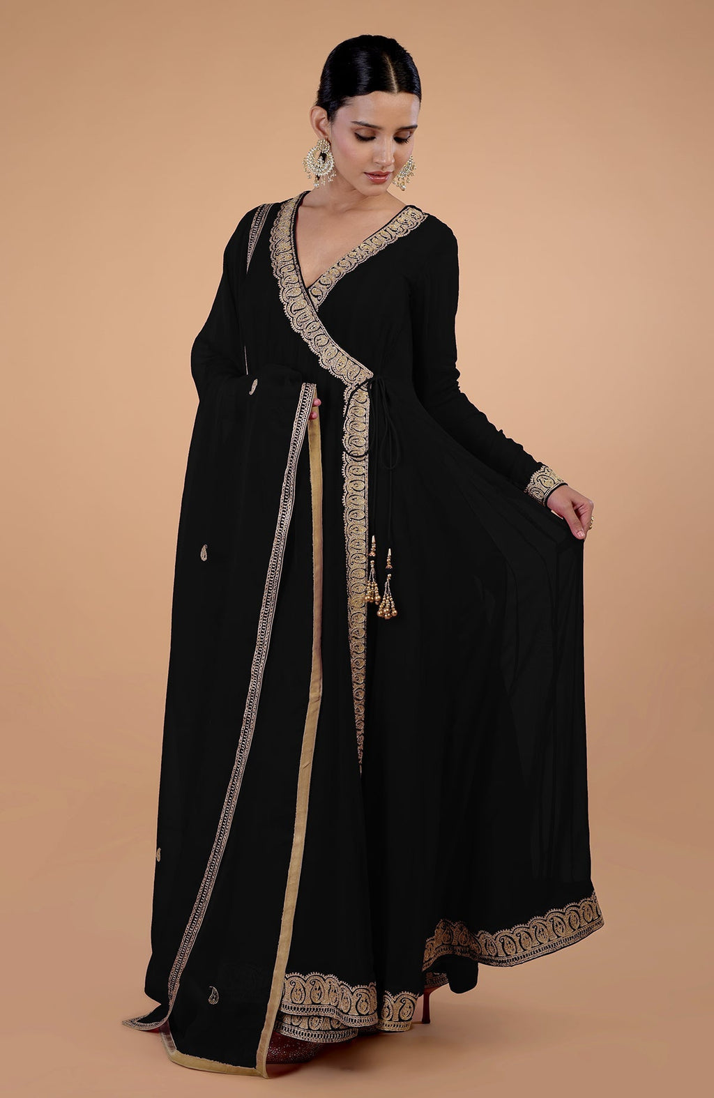 A woman models a black angrakha anarkali set with gold Kashmiri Tilla paisley embroidery.