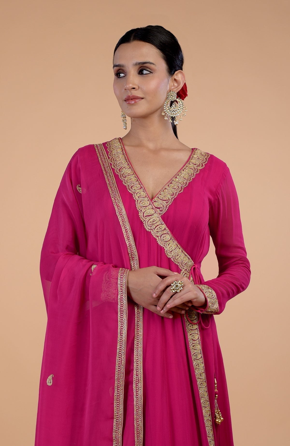 Woman in a raspberry pink angrakha anarkali set with gold paisley embroidery.