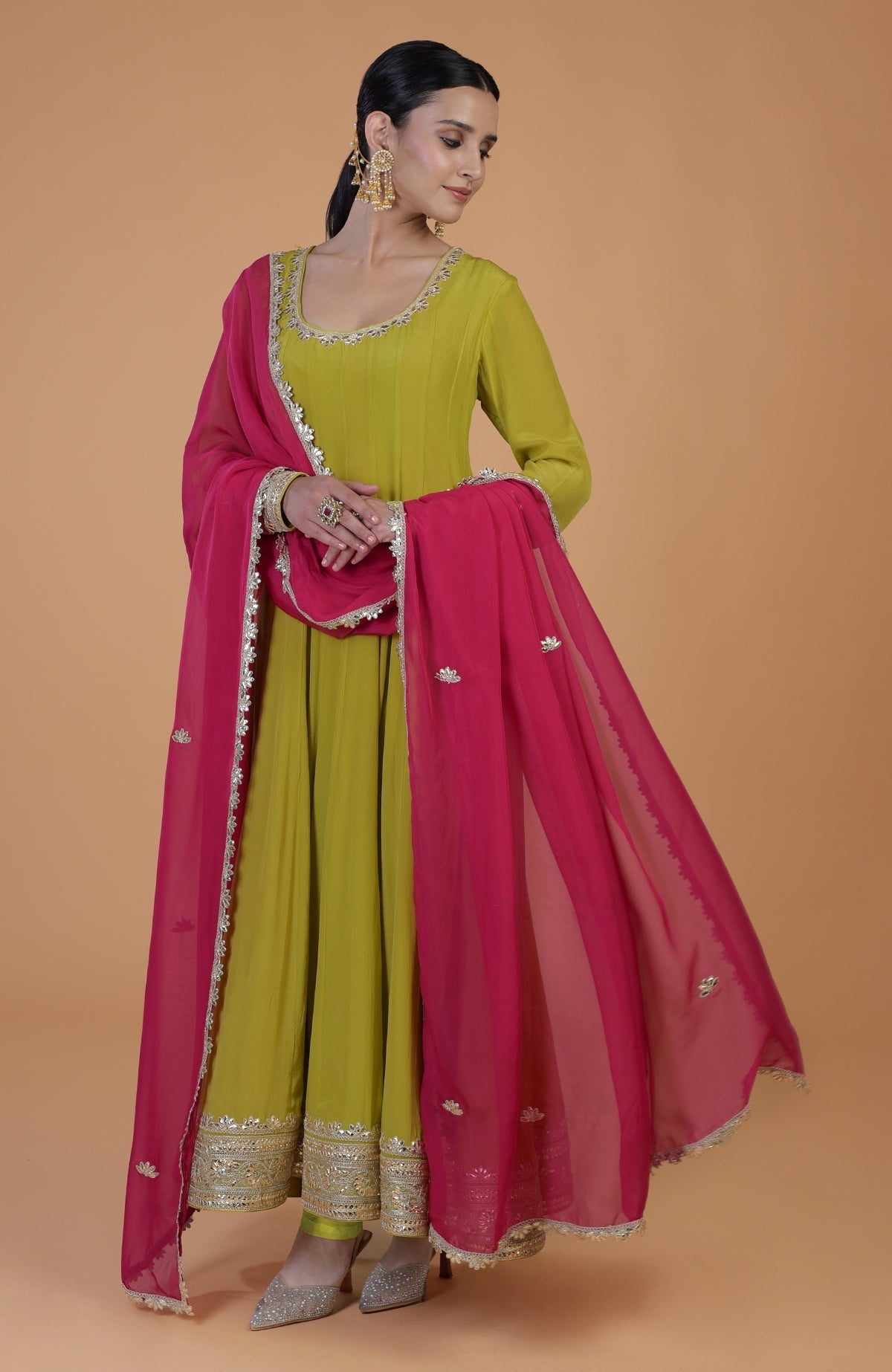 A woman models a citrus green anarkali set with a queen pink dupatta.