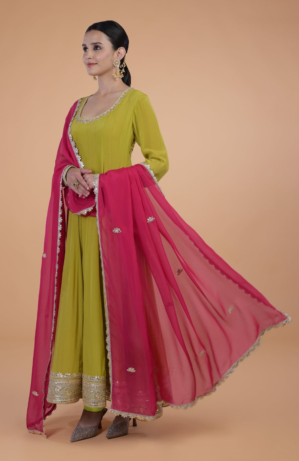 A woman models a citrus green Anarkali set with a queen pink dupatta.