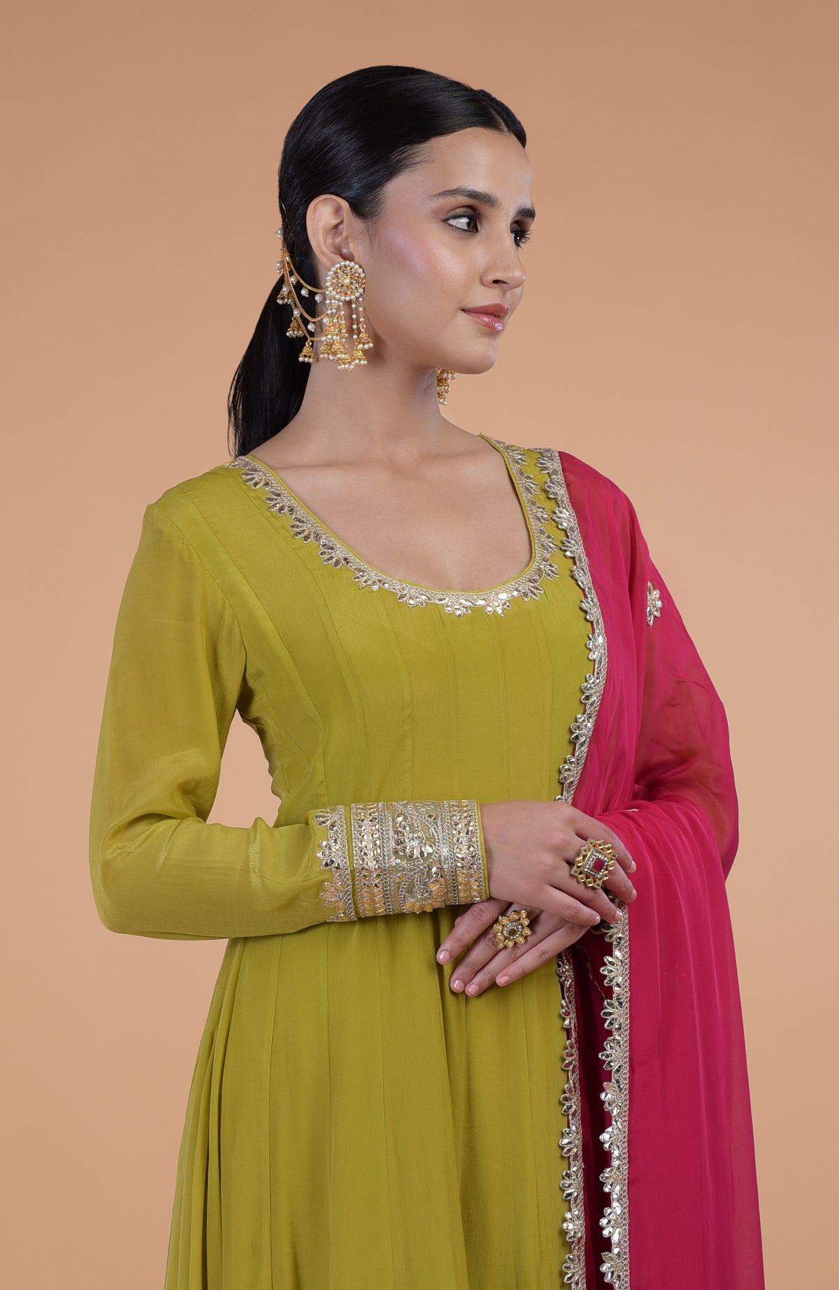A woman models a citrus green anarkali set with a queen pink dupatta.