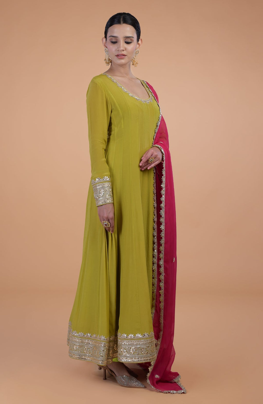 A woman models a citrus green Anarkali set with a queen pink dupatta.