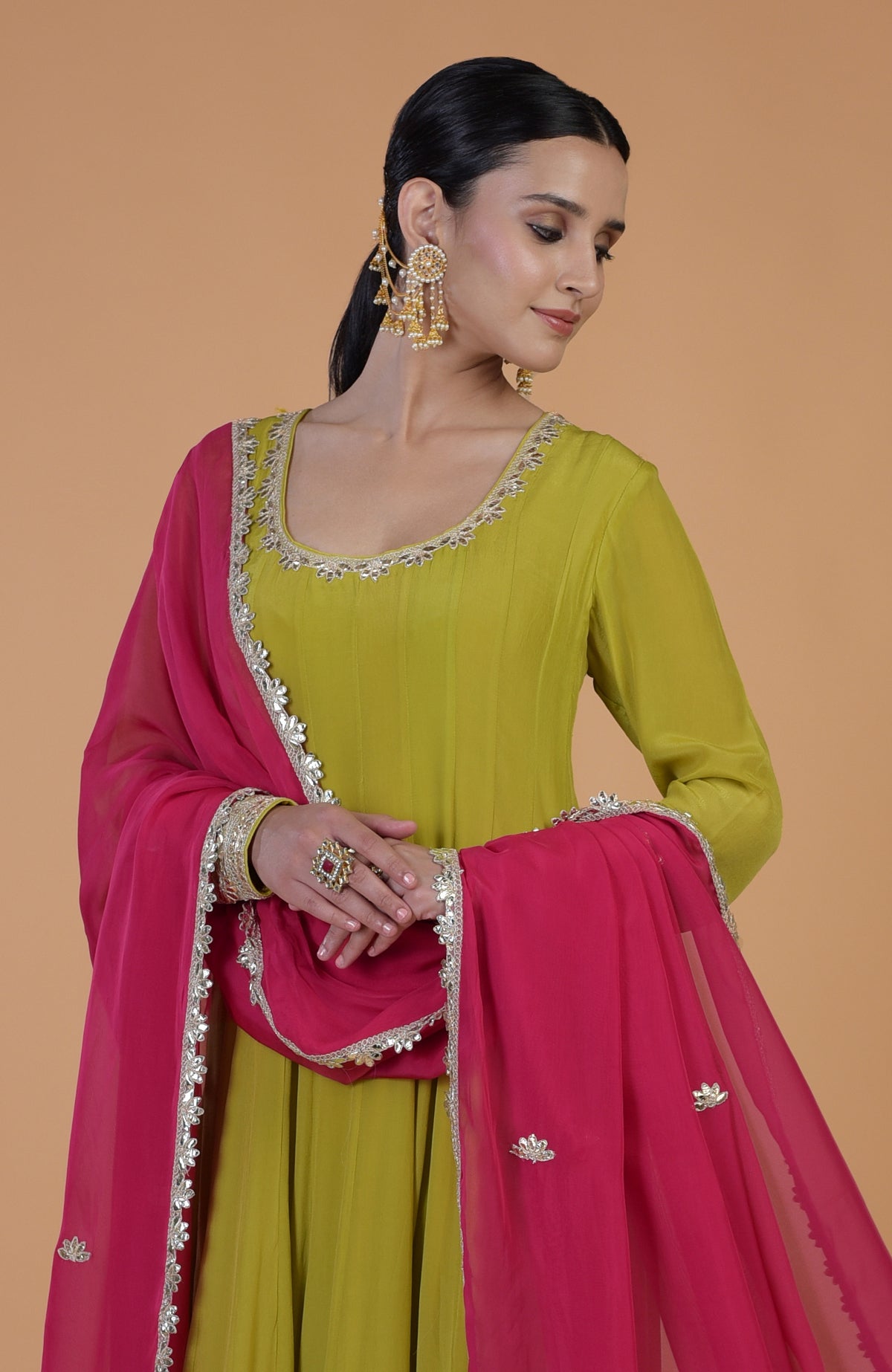 A woman models a citrus green Anarkali set with a Queen pink dupatta.