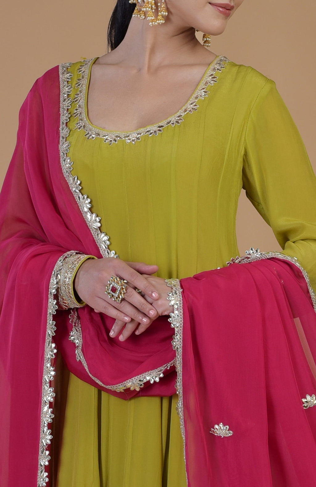 A woman models a citrus green anarkali set with a queen pink dupatta.