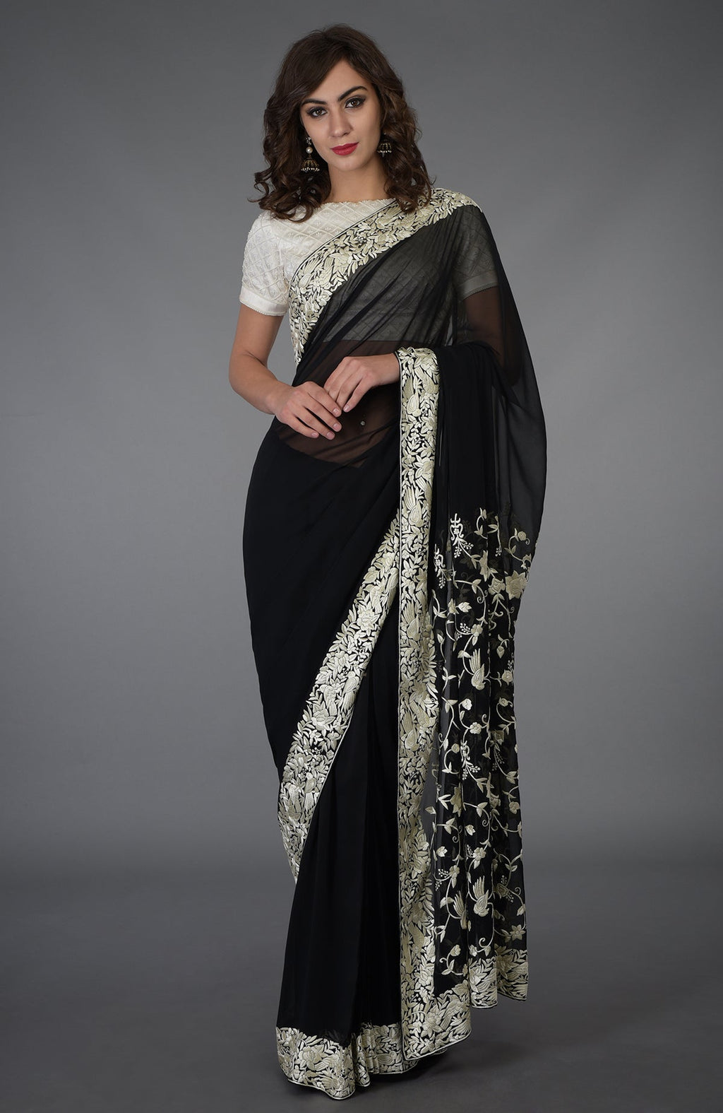 A woman models a black Parsi Gara hand-embroidered saree with ivory floral and bird motifs.