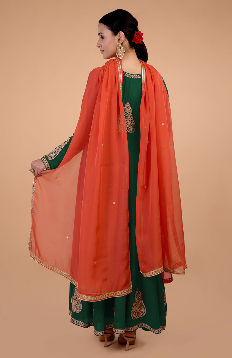 A woman models a bottle green anarkali set with an orange dupatta.