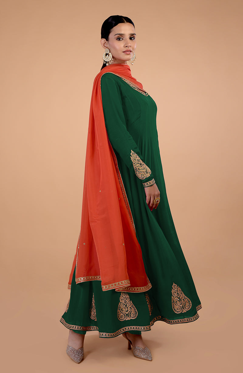 A woman models a bottle green anarkali set with an orange dupatta.