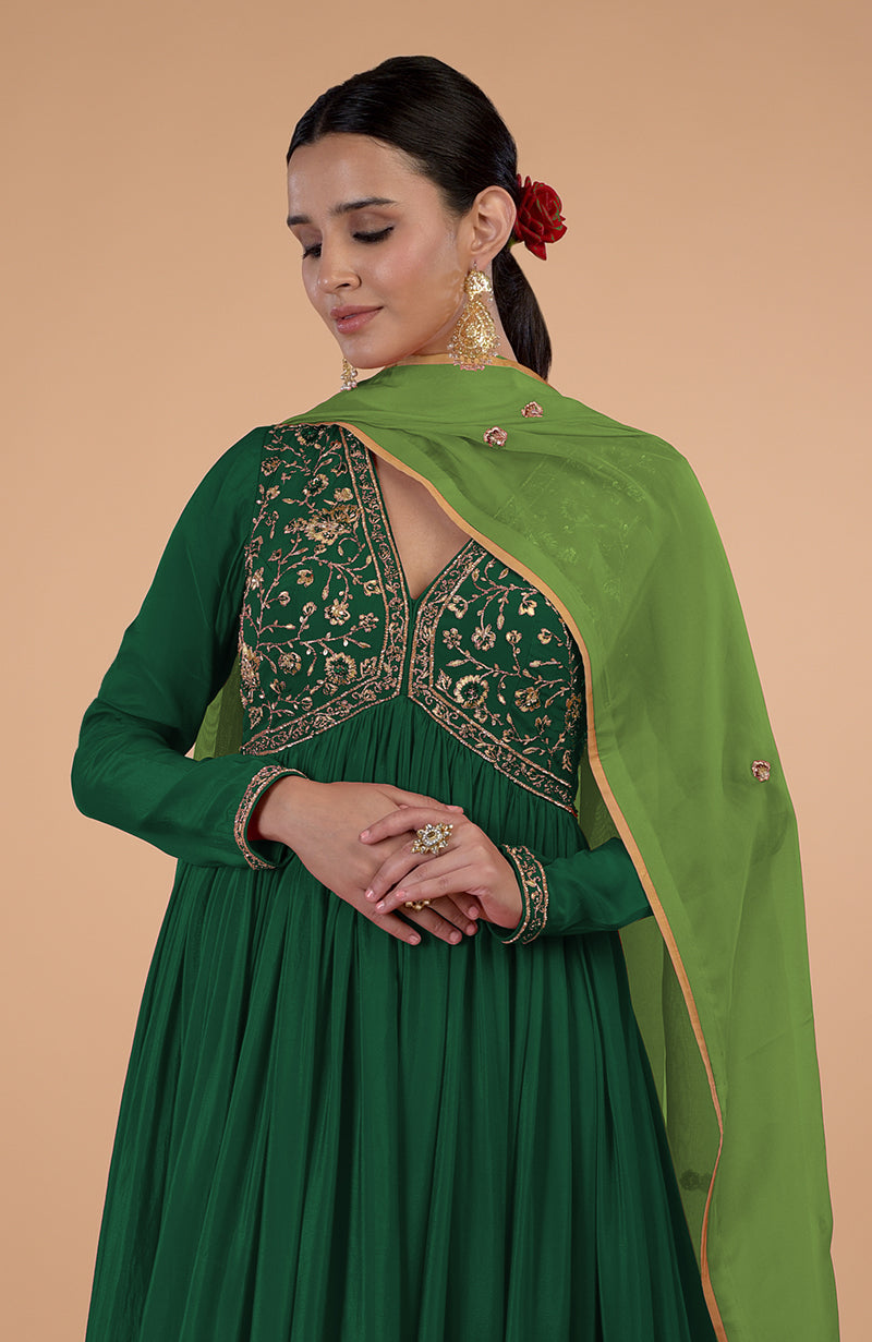 A woman in a bottle green embroidered anarkali set with a matching dupatta.