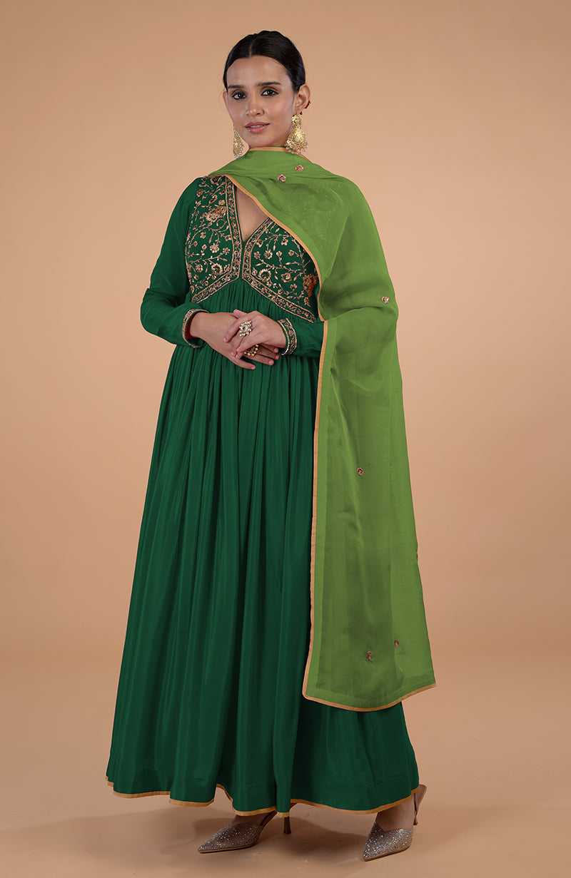 Woman in a green embroidered Anarkali suit with a matching dupatta.