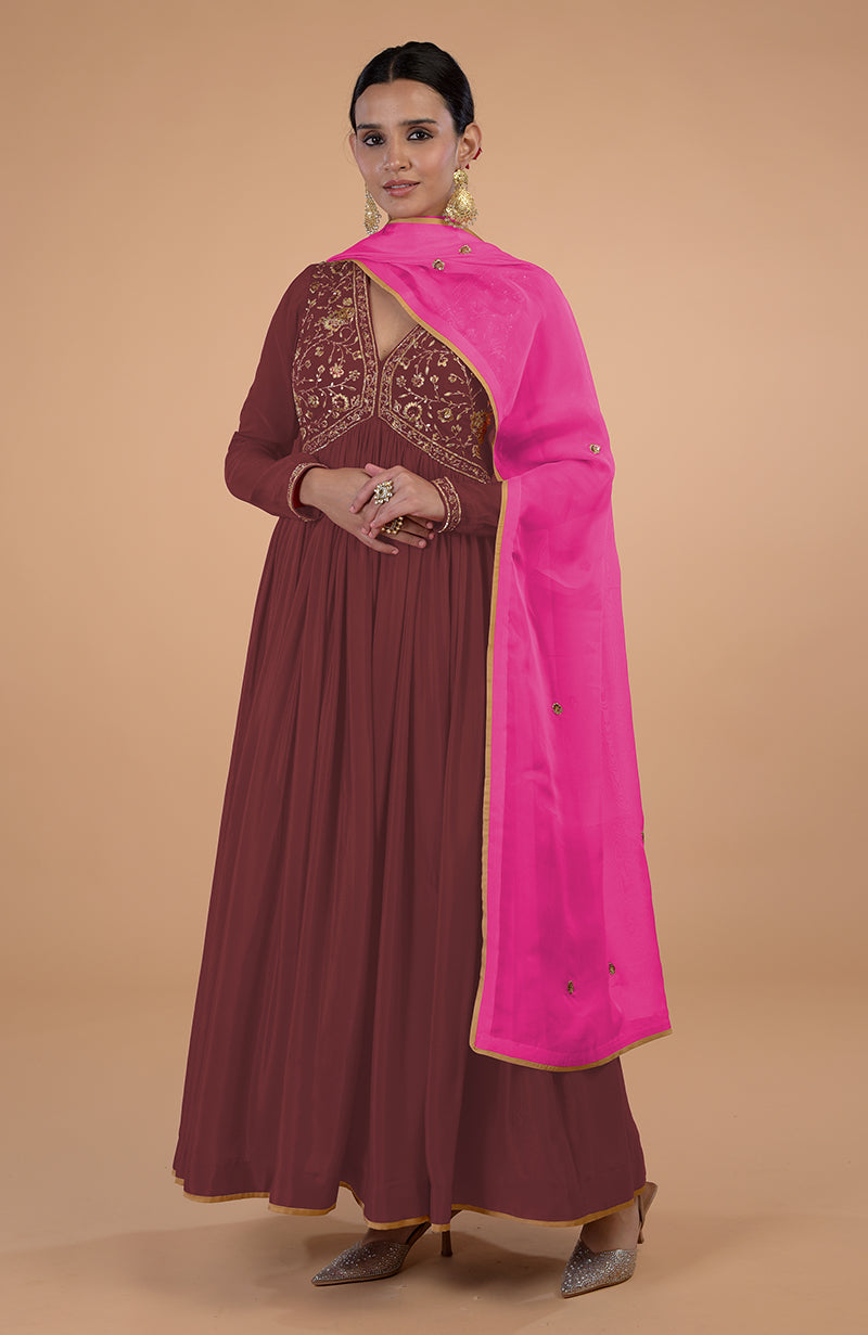 A woman models a red-orange zardozi and resham embroidered anarkali set with a pink dupatta.