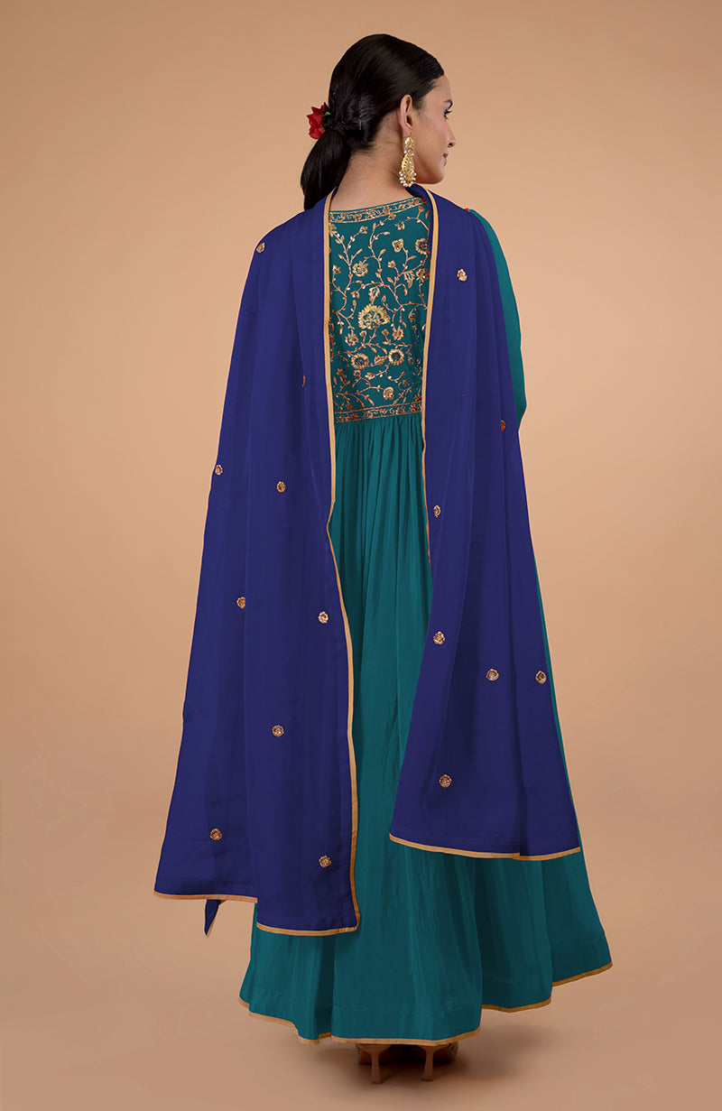 A woman from behind wears a teal-blue anarkali with a royal blue dupatta.