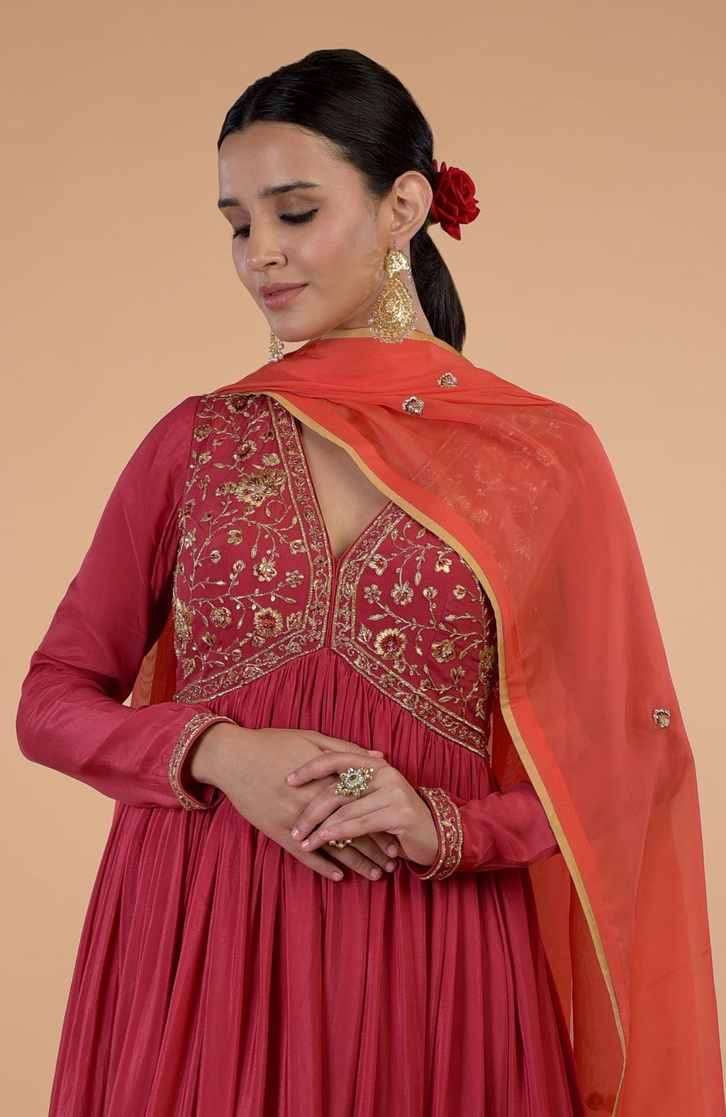 A woman models a red and orange embroidered Anarkali set with a matching dupatta.