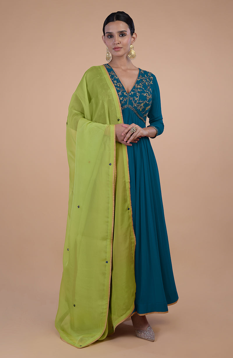 A woman models a peacock blue anarkali set with green zardozi embroidery and a green dupatta.