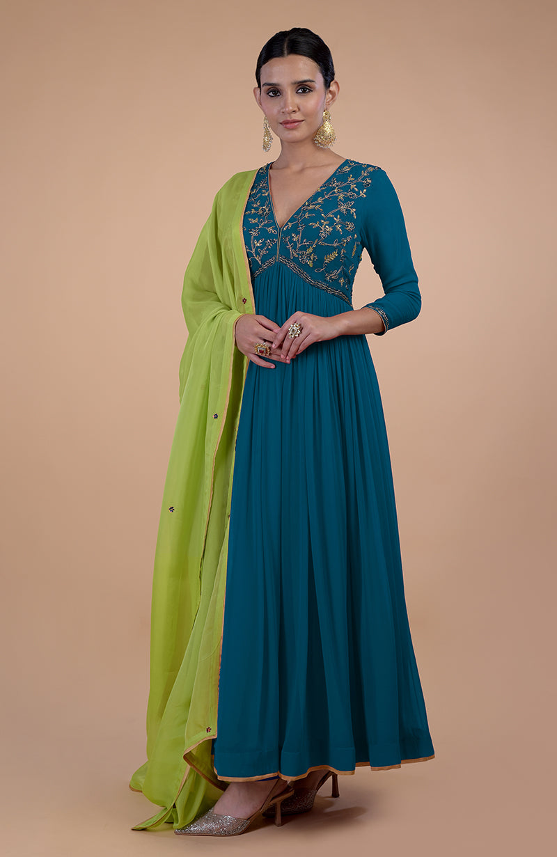 A woman models a peacock blue anarkali with gold embroidery and a green dupatta.