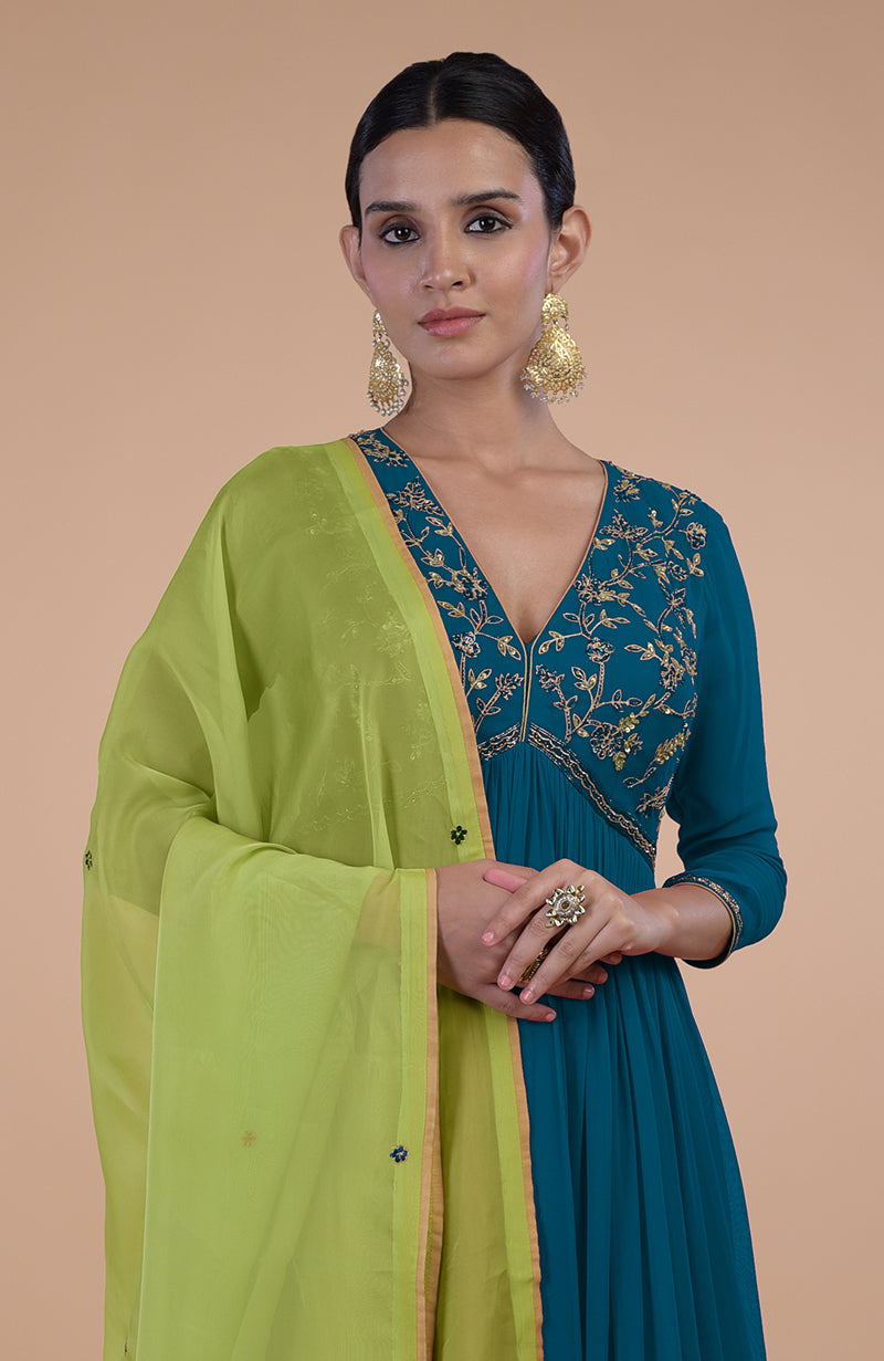 A woman models a peacock blue anarkali with green zardozi embroidery and a green dupatta.