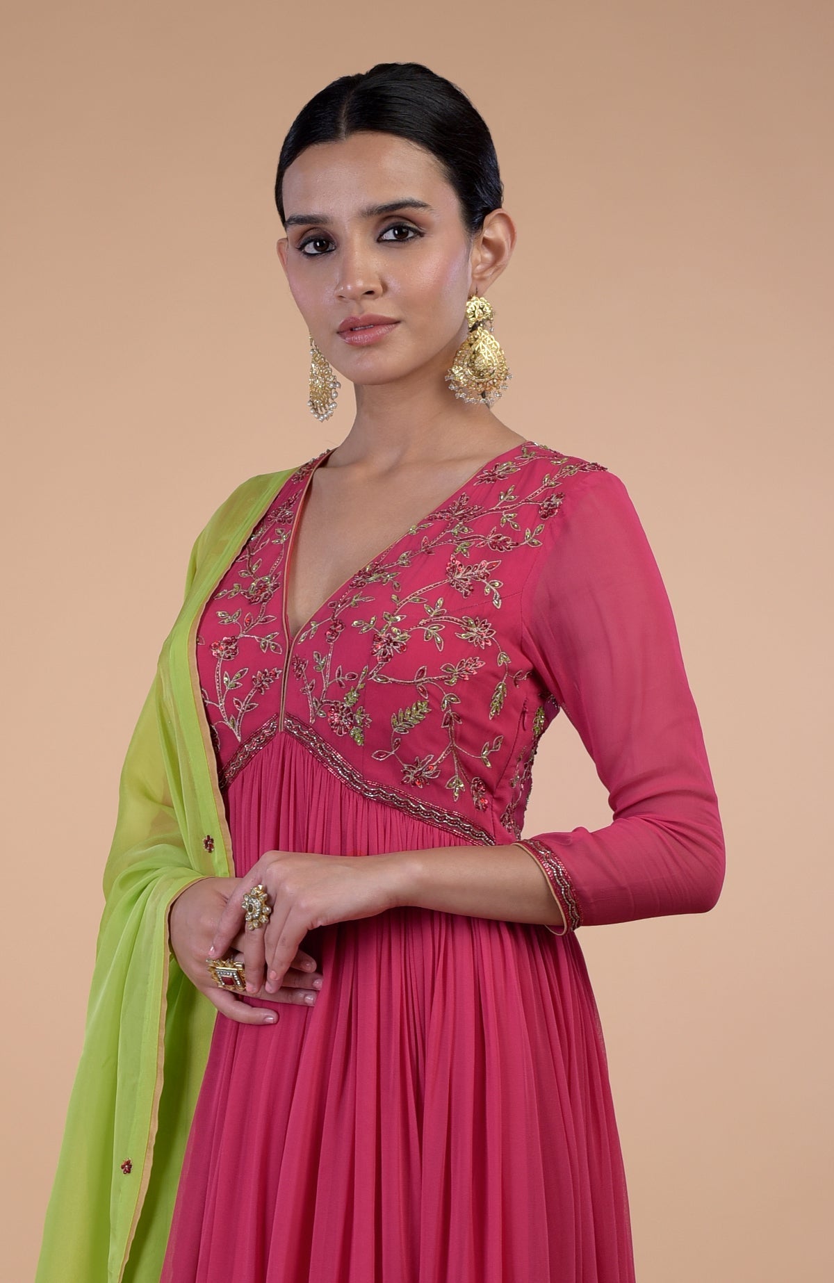 A woman models a pink anarkali set with green zardozi embroidery and a green dupatta.