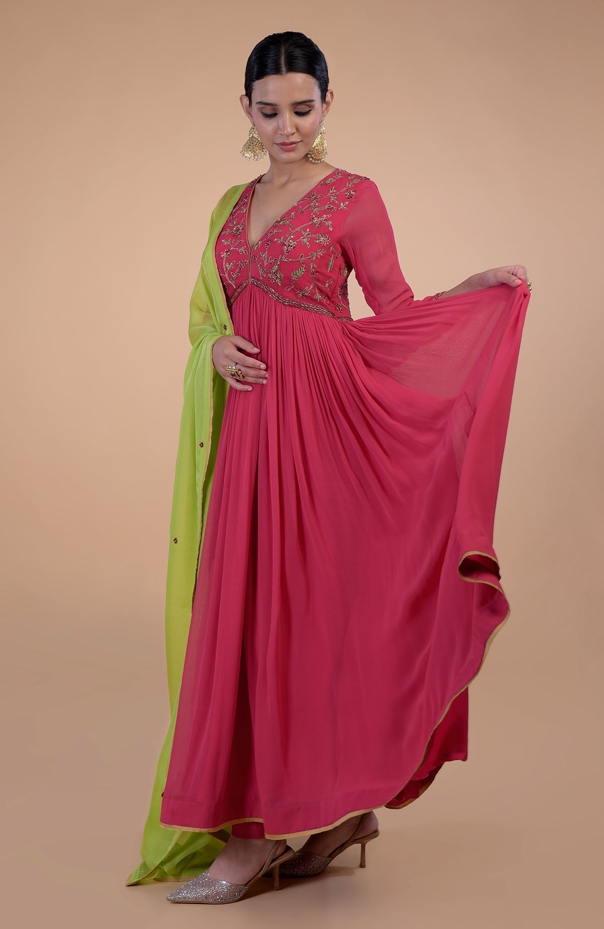 A woman models a pink zardozi embroidered anarkali set with a green dupatta.