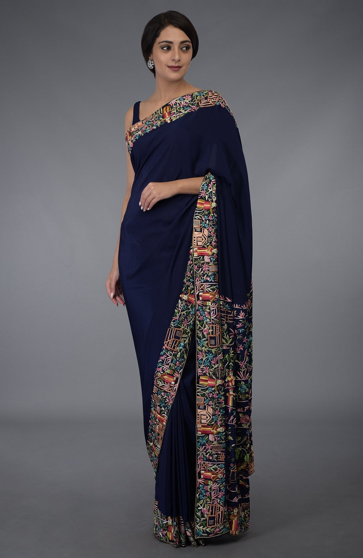 Midnight blue Parsi Gara hand-embroidered saree with colorful floral and figural motifs.