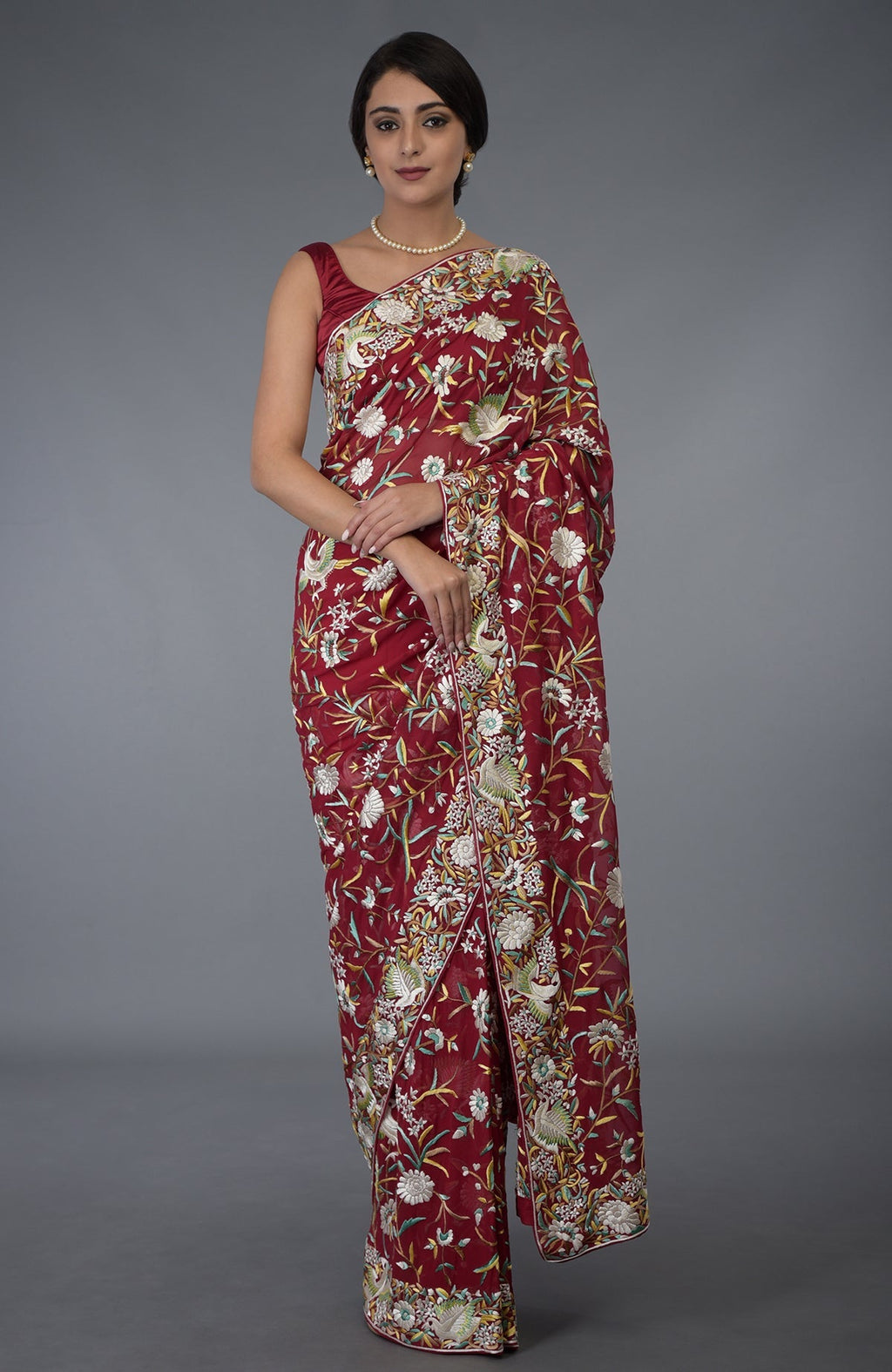 A woman models a red Parsi Gara hand-embroidered saree with floral and bird motifs.