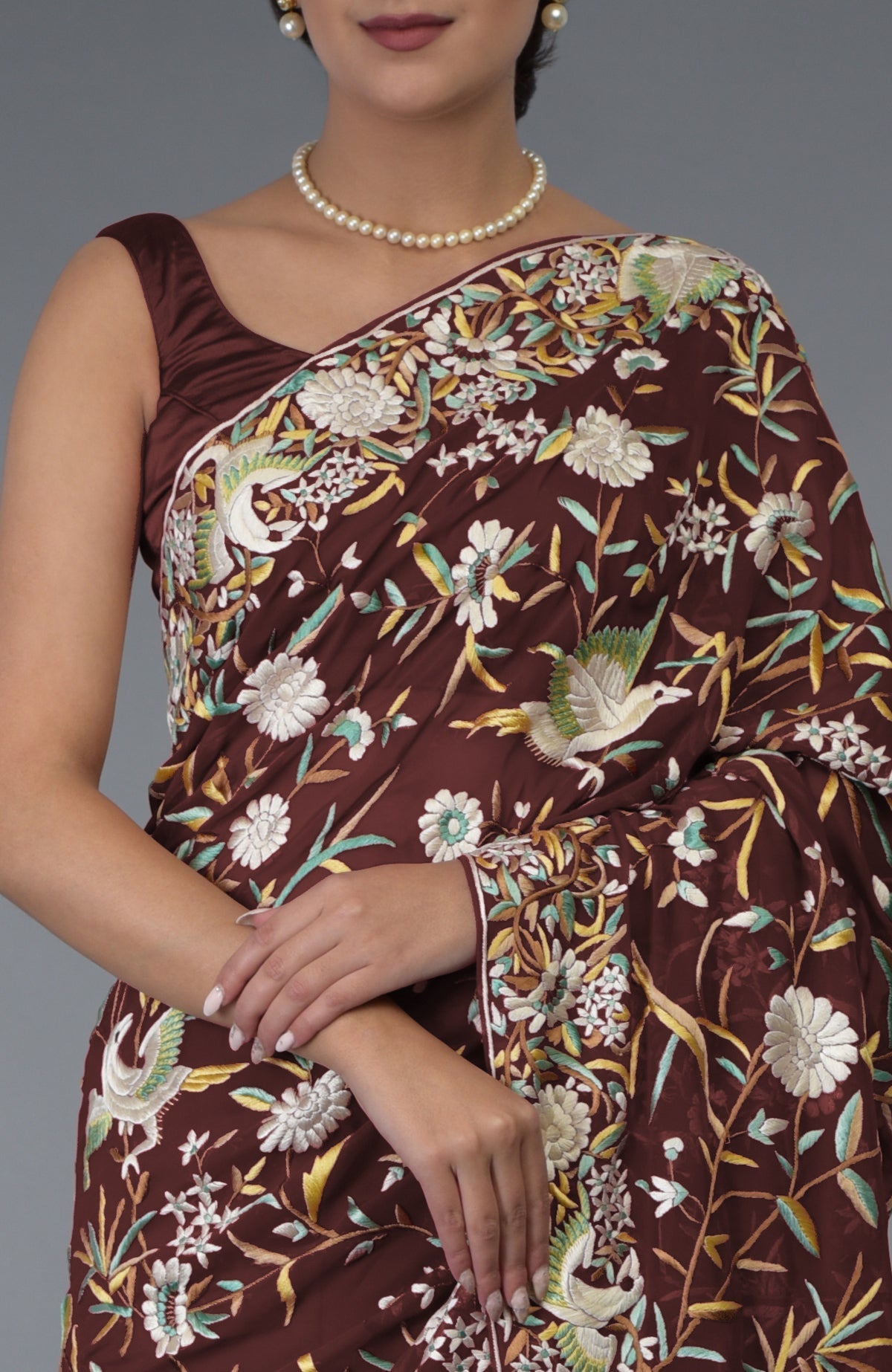A woman models a marsala Parsi Gara hand-embroidered saree with birds and floral patterns.
