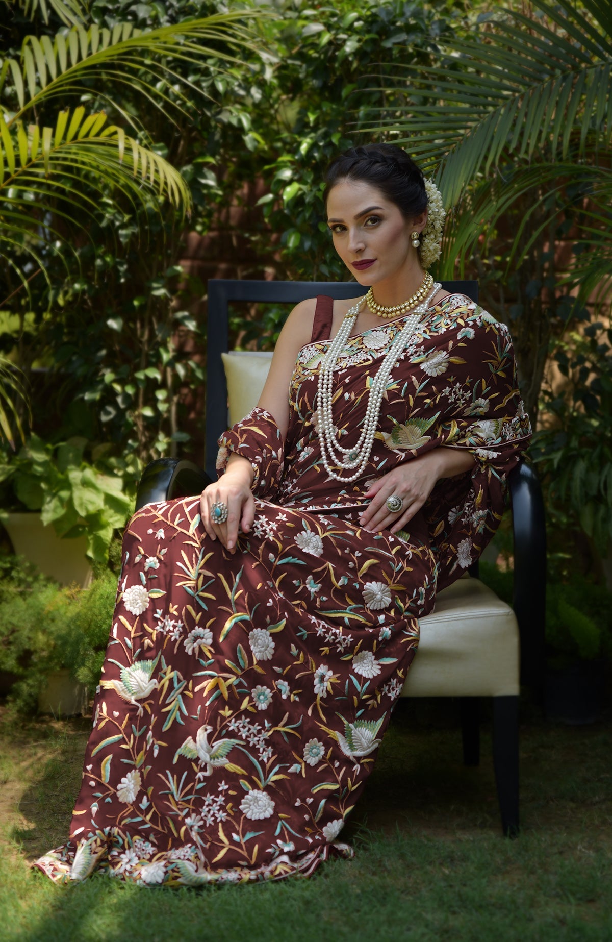 Woman in a maroon Parsi Gara hand-embroidered saree with bird and floral motifs.