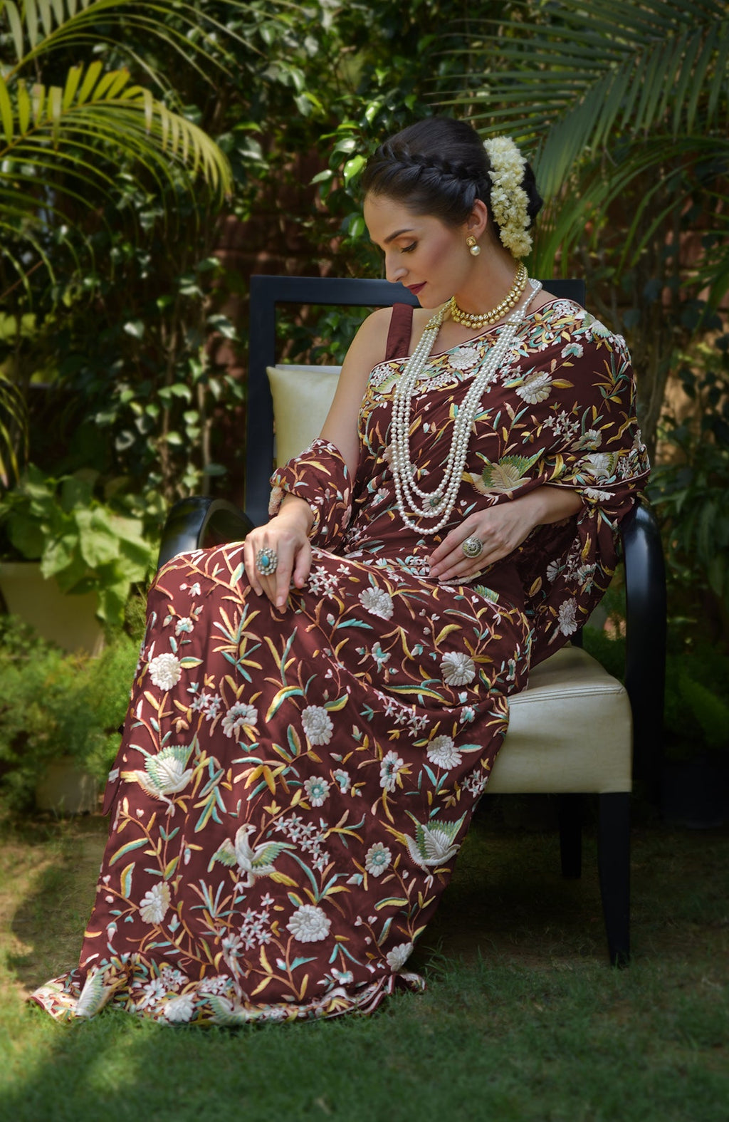 A woman models a marsala Parsi Gara hand-embroidered saree with floral and bird motifs.