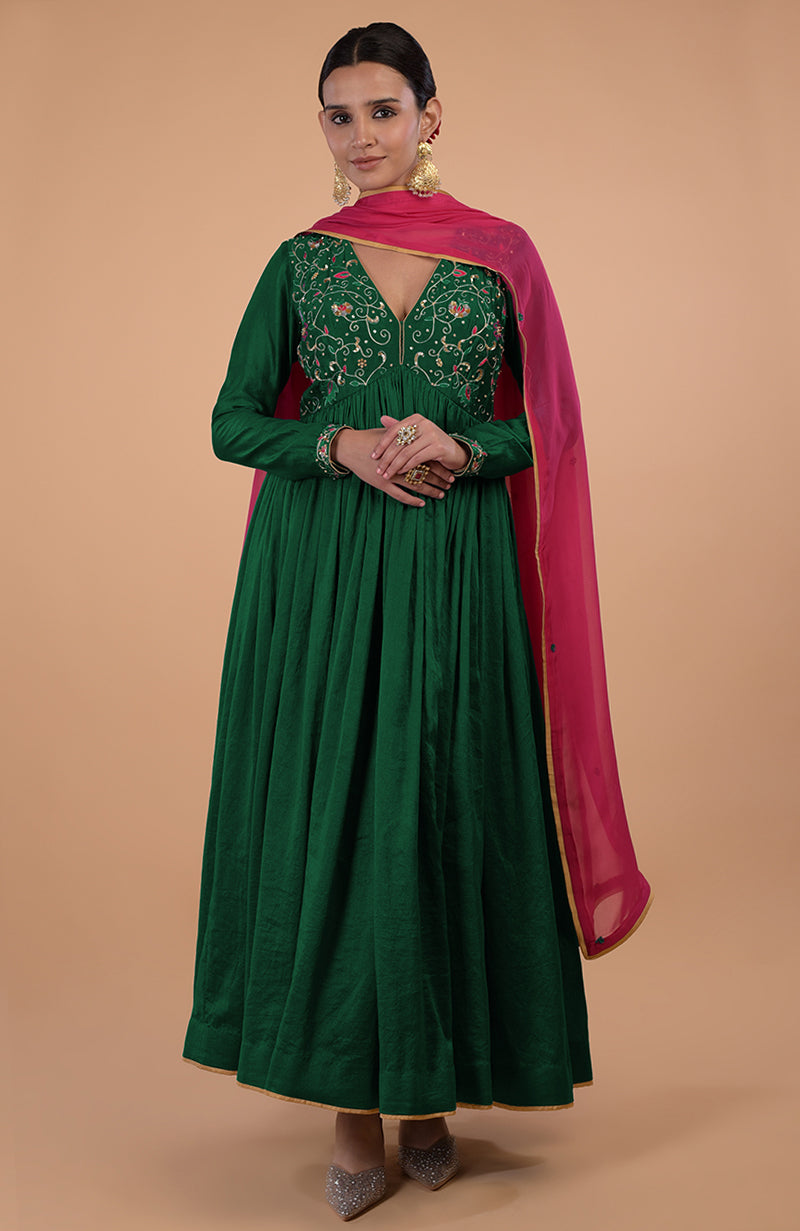A woman models a green anarkali set with a pink dupatta and embroidered bodice.