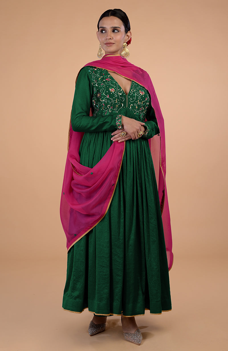 A woman models a bottle green anarkali with pink dupatta and zardozi embroidery.