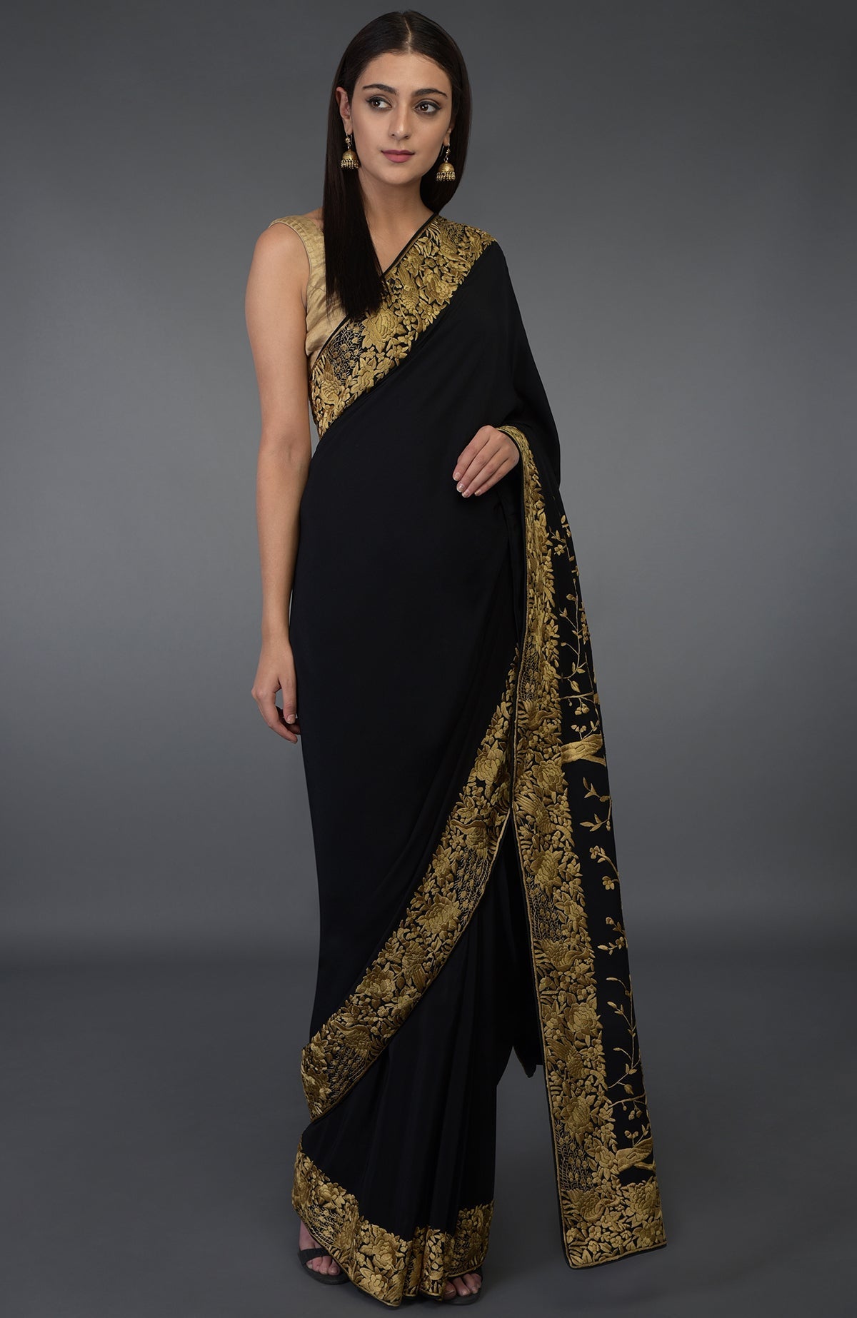 A woman models a black saree with gold Parsi Gara hand embroidery.