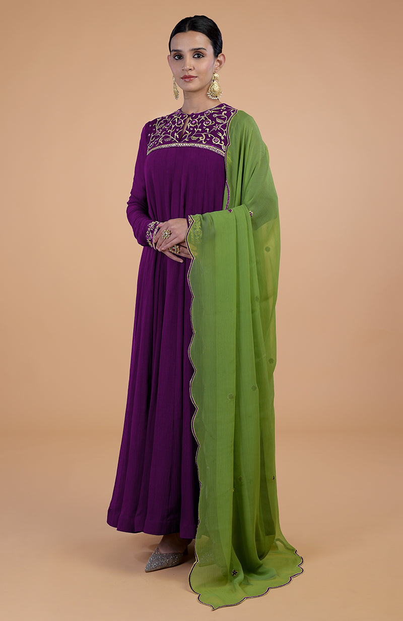 A woman models a purple anarkali set with a green dupatta and embroidered details.