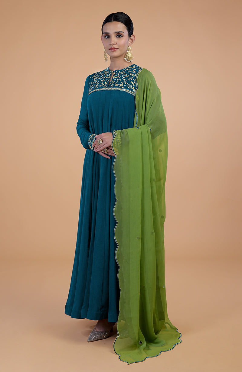 A woman models a teal-green anarkali set with gold embroidery and a green dupatta.