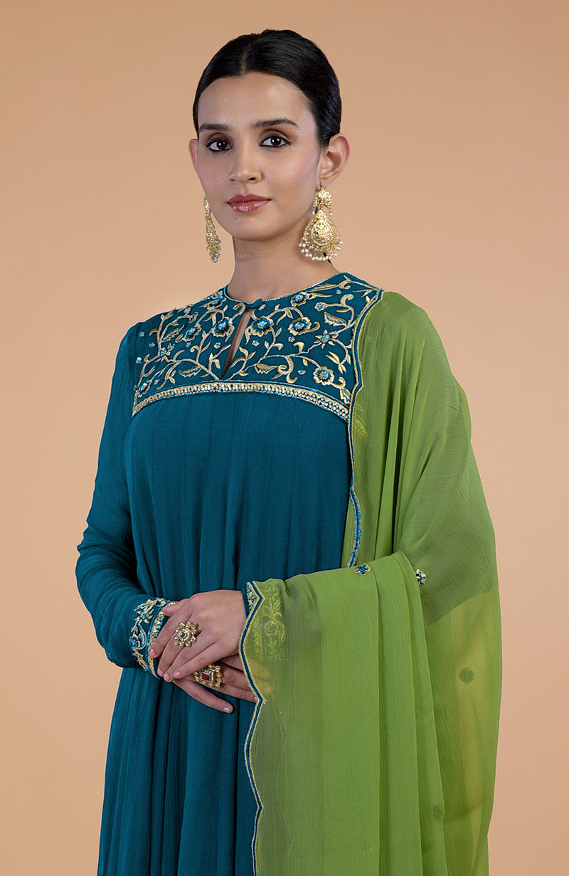 A woman models a teal-green anarkali set with gold and blue embroidery.