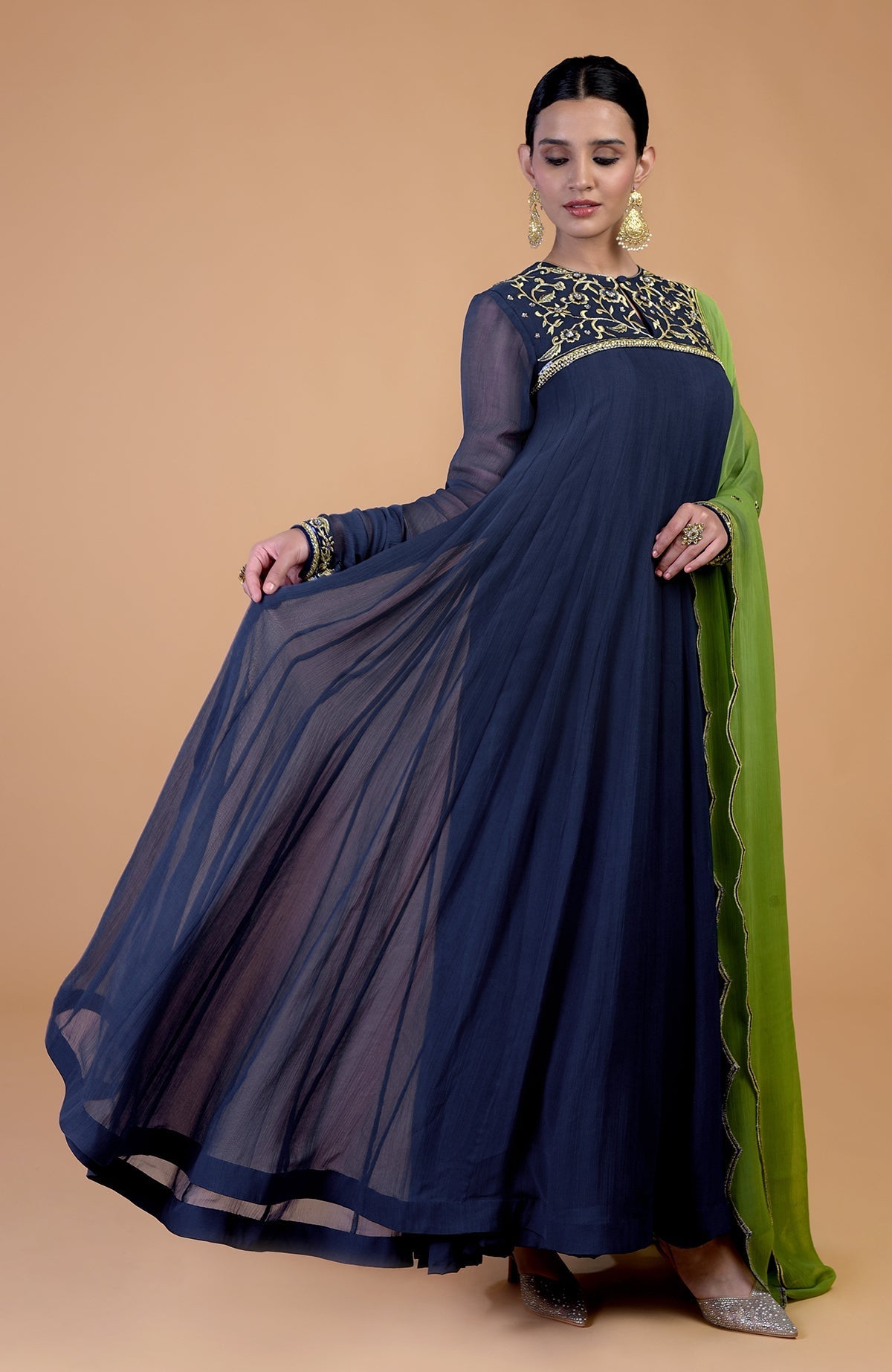 A woman models a midnight blue anarkali set with green resham and zardozi embroidery.