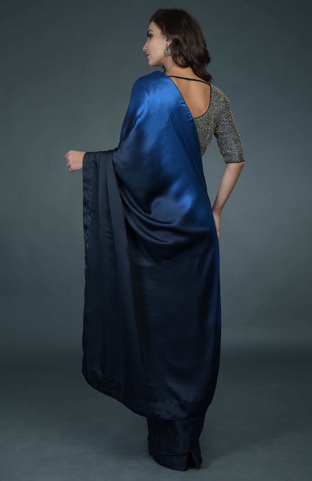 A woman models a midnight blue ombre saree with a gold zardozi work blouse.