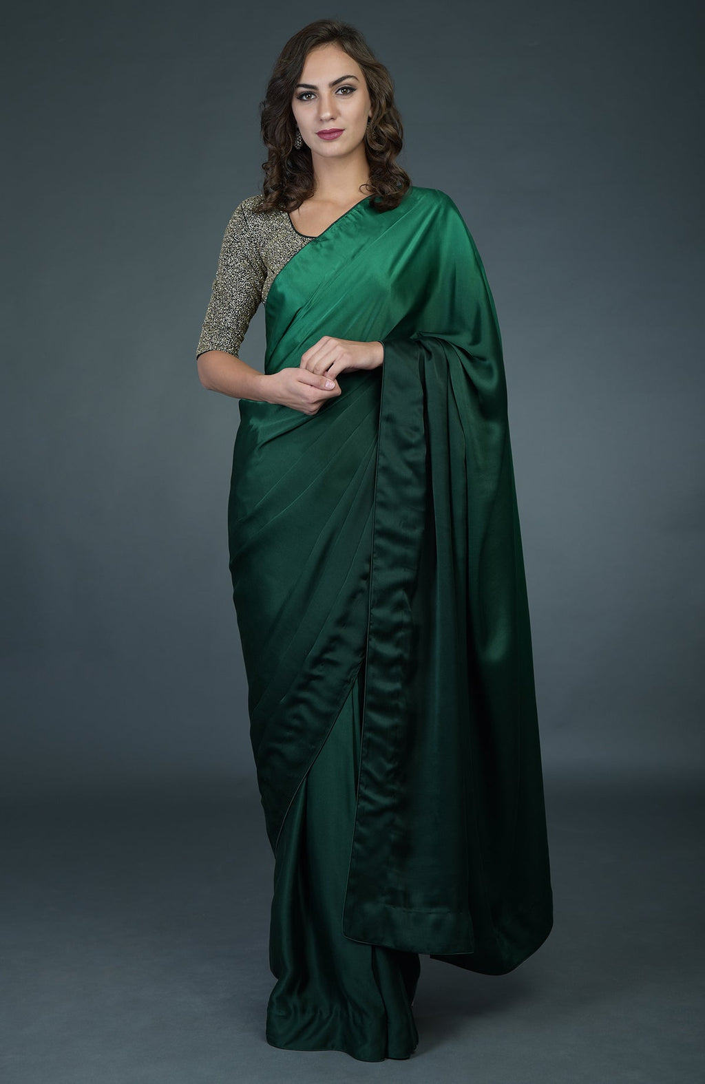 A woman models a bottle green ombre satin silk saree with a zardozi work blouse.