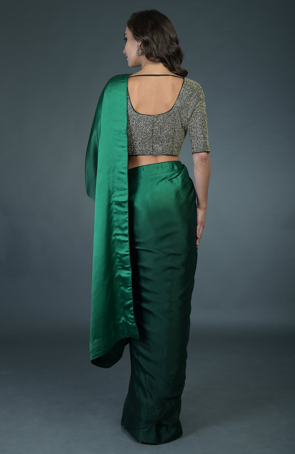 A woman from behind wears a bottle green ombre saree with a gold zardozi work blouse.