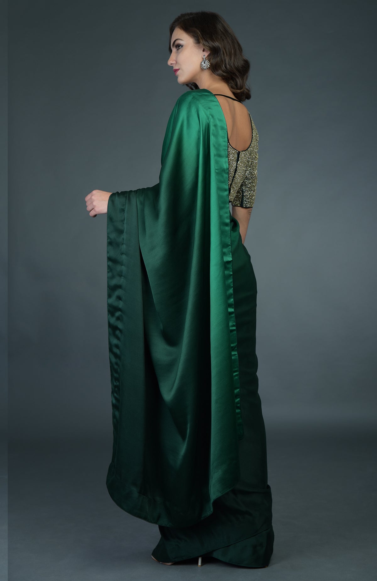 A woman models a bottle green ombre saree with a gold zardozi work blouse.