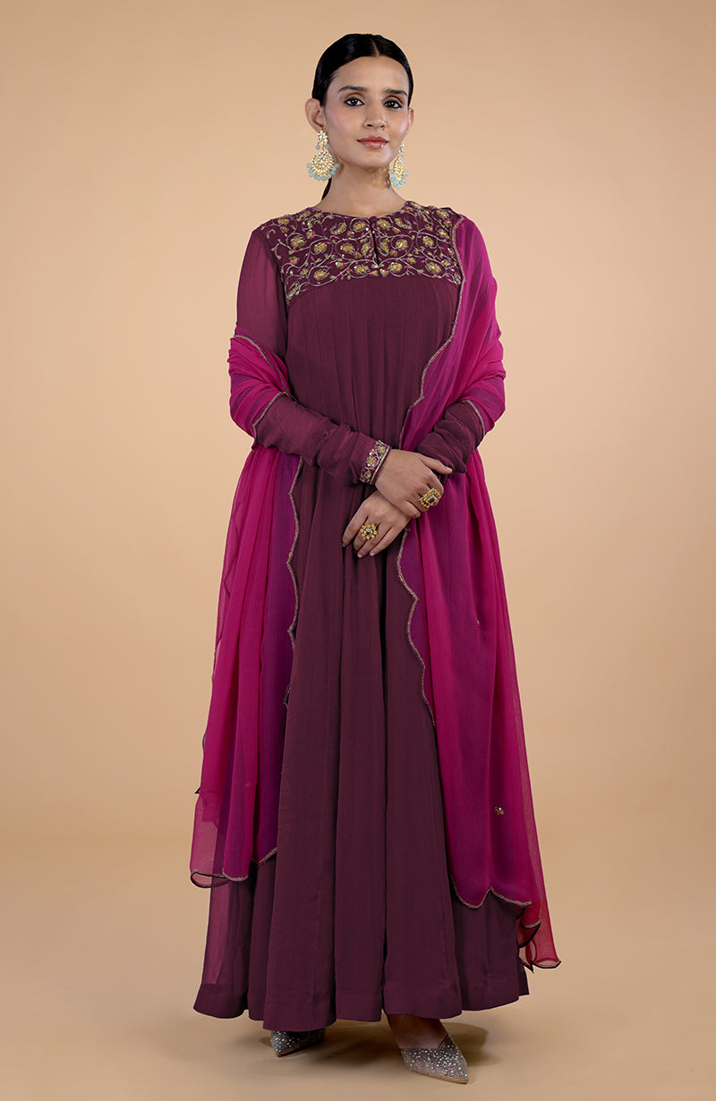 A woman models a burgundy-pink zardozi embroidered anarkali set with a matching dupatta.